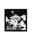 Screen printed image of person being pulled into a flying saucer at night amongst trees and mountains. White ink on black background. Art by Print Ritual.